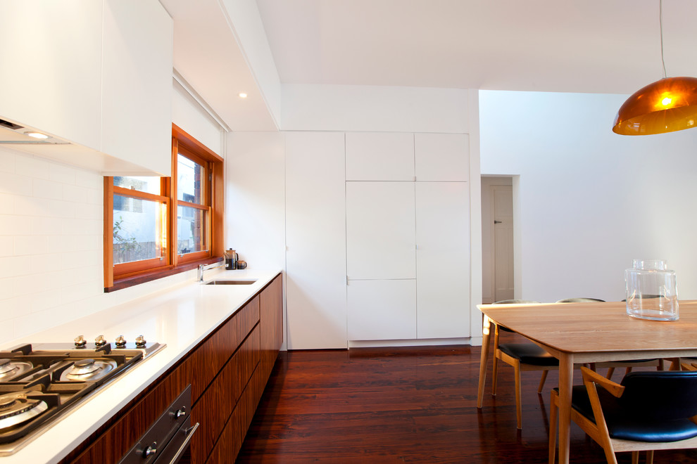 Inspiration for a contemporary l-shaped eat-in kitchen in Other with an undermount sink, flat-panel cabinets, medium wood cabinets, white splashback, subway tile splashback and stainless steel appliances.
