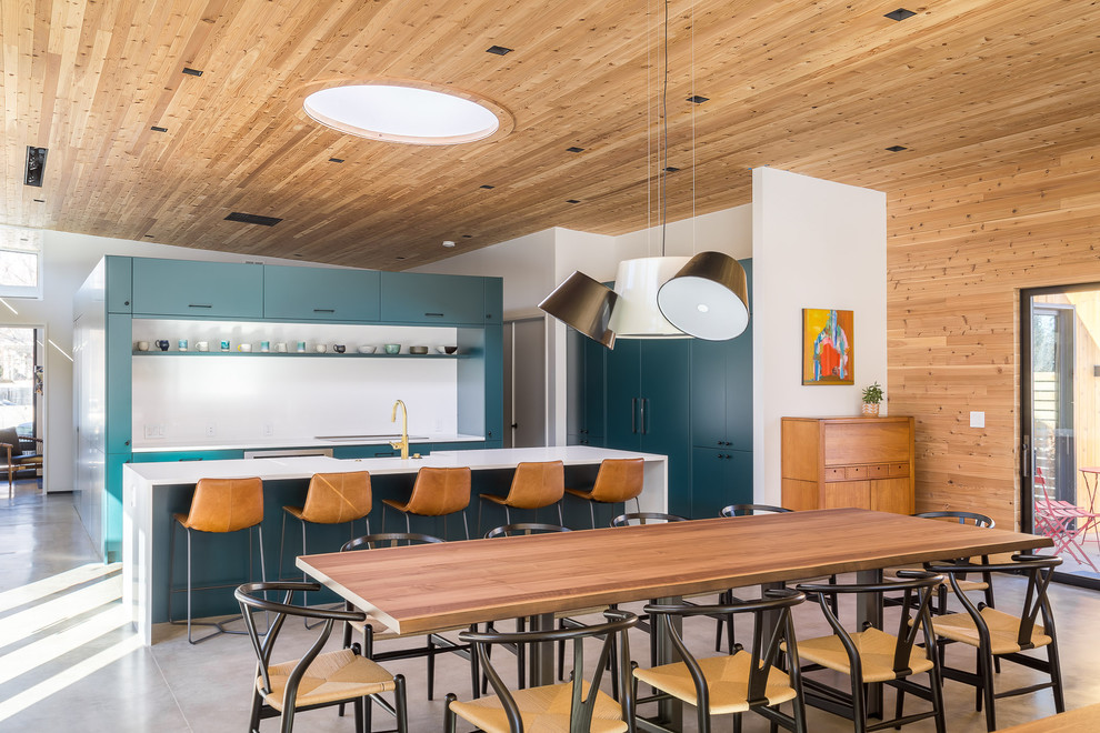 Example of a large trendy u-shaped concrete floor and gray floor eat-in kitchen design in Denver with a farmhouse sink, flat-panel cabinets, green cabinets, quartz countertops, white backsplash, paneled appliances, an island and white countertops