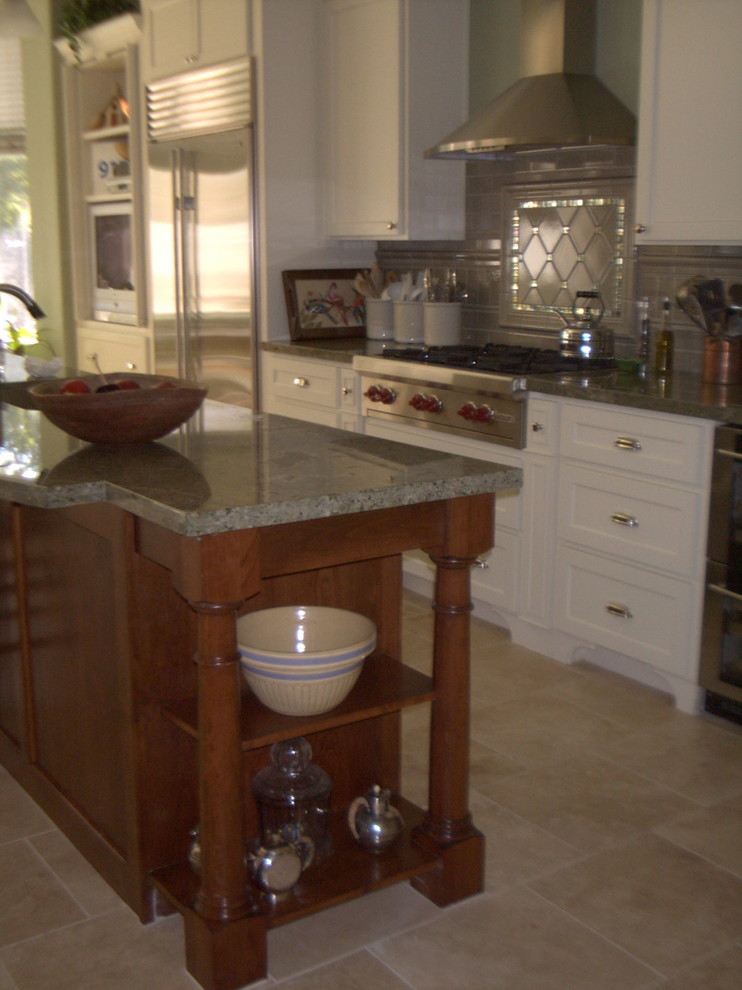 Foto på ett mellanstort vintage kök, med en köksö, luckor med infälld panel, vita skåp, granitbänkskiva, grönt stänkskydd, stänkskydd i keramik och travertin golv