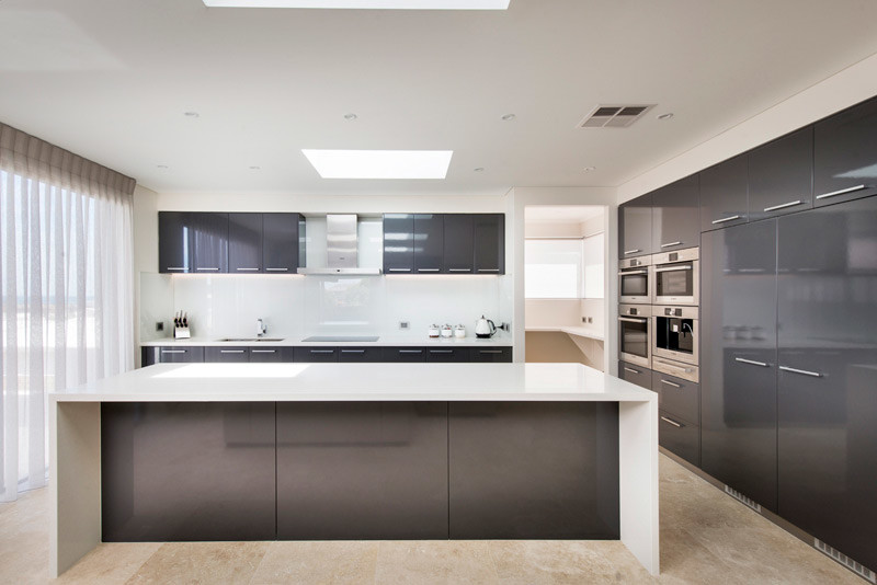 Moderne Küche mit Doppelwaschbecken, flächenbündigen Schrankfronten, grauen Schränken, Küchenrückwand in Weiß, Glasrückwand, Küchengeräten aus Edelstahl und Kücheninsel in Perth