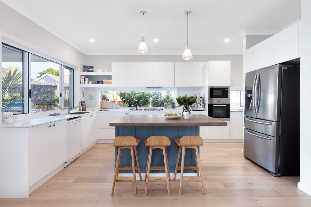 Inspiration for a contemporary u-shaped medium tone wood floor and beige floor kitchen remodel in Sydney with a double-bowl sink, flat-panel cabinets, white cabinets, wood countertops, gray backsplash, stainless steel appliances, an island and white countertops