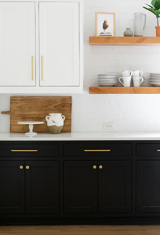Bild på ett stort funkis vit vitt kök, med skåp i shakerstil, svarta skåp, vitt stänkskydd, ljust trägolv, en köksö och brunt golv