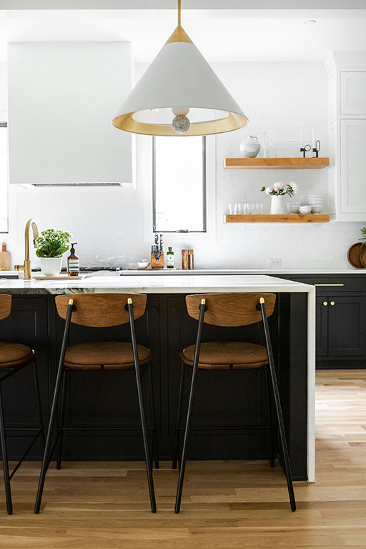 Modelo de cocina minimalista grande abierta con armarios estilo shaker, puertas de armario negras, salpicadero blanco, suelo de madera clara, una isla, suelo marrón y encimeras blancas