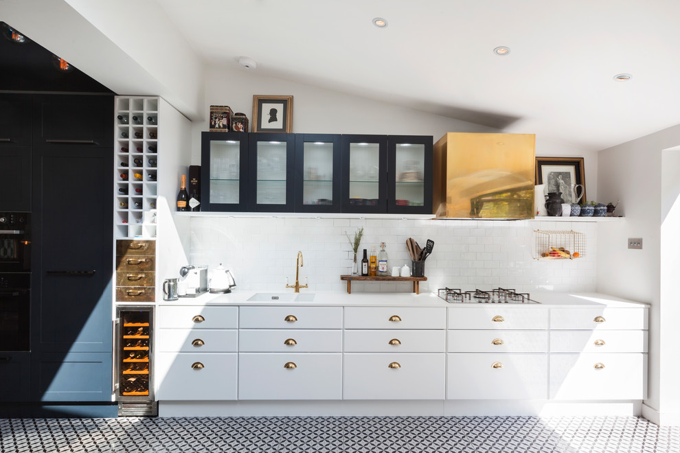 Einzeilige Moderne Küche mit flächenbündigen Schrankfronten, weißen Schränken, Küchenrückwand in Weiß, Rückwand aus Metrofliesen, buntem Boden und Doppelwaschbecken in London