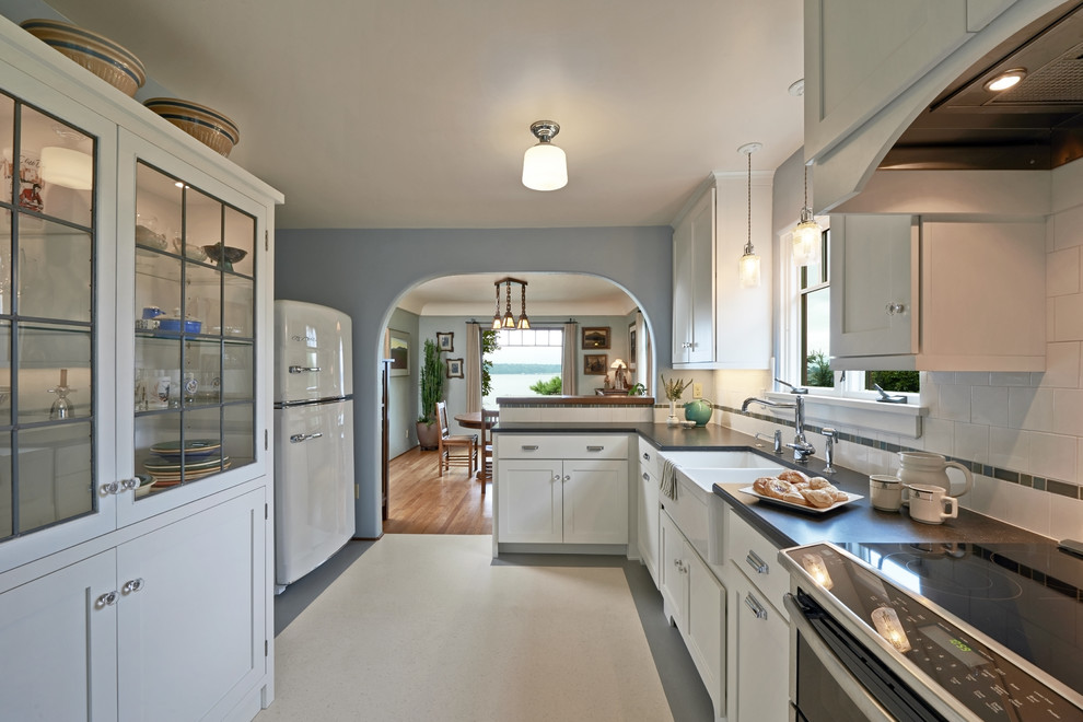 Inspiration for a large traditional galley kitchen/diner in Seattle with a belfast sink, recessed-panel cabinets, white cabinets, composite countertops, white splashback, ceramic splashback, stainless steel appliances, lino flooring and no island.