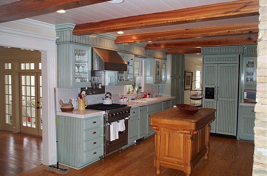 Lantlig inredning av ett mellanstort kök, med en nedsänkt diskho, blå skåp, kaklad bänkskiva, vitt stänkskydd, stänkskydd i keramik, rostfria vitvaror, mellanmörkt trägolv och en köksö