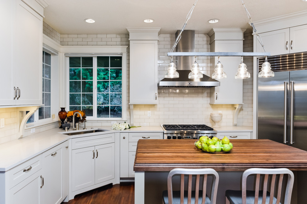 Exempel på ett mellanstort klassiskt flerfärgad flerfärgat kök, med en undermonterad diskho, luckor med infälld panel, vita skåp, träbänkskiva, vitt stänkskydd, stänkskydd i tunnelbanekakel, rostfria vitvaror, mellanmörkt trägolv, en köksö och brunt golv
