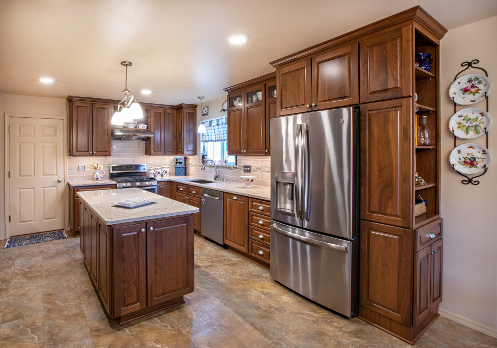 Mid-sized elegant l-shaped vinyl floor and brown floor eat-in kitchen photo in Other with an undermount sink, raised-panel cabinets, brown cabinets, quartz countertops, beige backsplash, subway tile backsplash, stainless steel appliances, an island and beige countertops