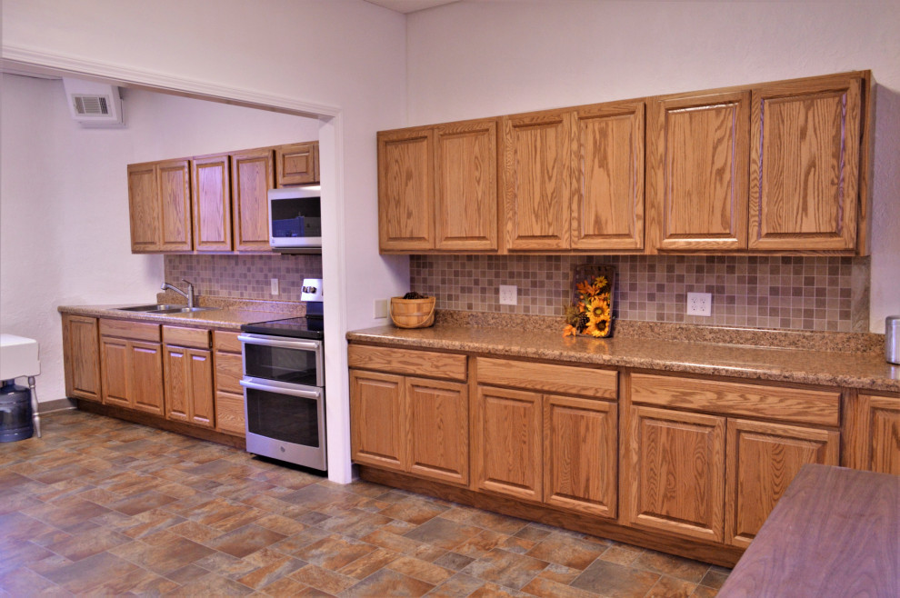 Bild på ett mellanstort rustikt brun linjärt brunt kök och matrum, med en nedsänkt diskho, luckor med upphöjd panel, skåp i ljust trä, laminatbänkskiva, brunt stänkskydd, rostfria vitvaror, laminatgolv och flerfärgat golv