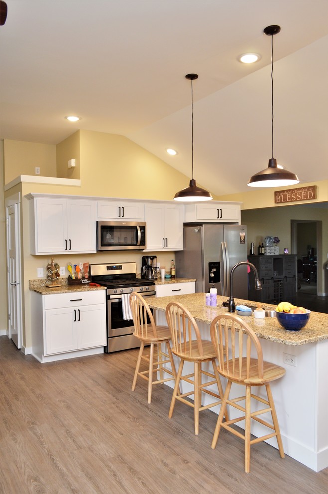 Exempel på ett mellanstort klassiskt brun linjärt brunt kök med öppen planlösning, med en undermonterad diskho, skåp i shakerstil, vita skåp, granitbänkskiva, rostfria vitvaror, mellanmörkt trägolv, en köksö och brunt golv