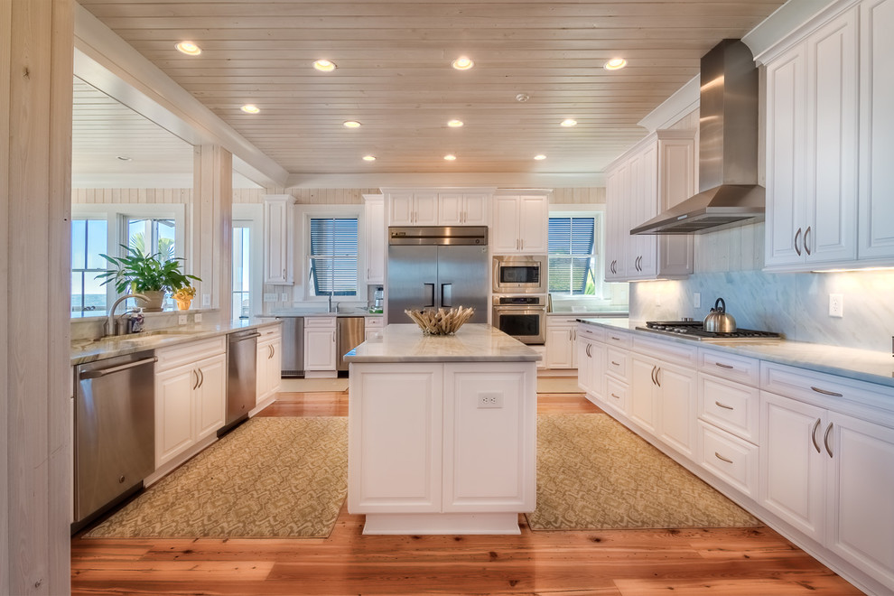 Maritime Küche in U-Form mit Unterbauwaschbecken, profilierten Schrankfronten, weißen Schränken, Küchenrückwand in Grau und Küchengeräten aus Edelstahl in Charleston