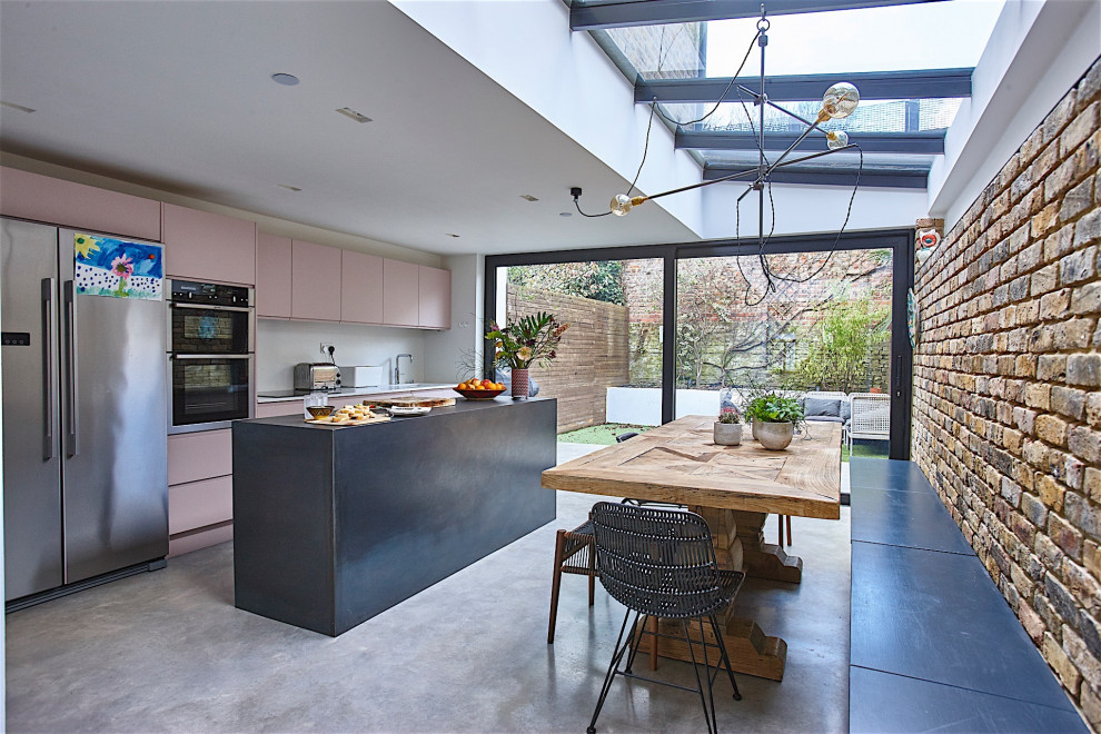 Ispirazione per un cucina con isola centrale contemporaneo con ante rosa e pavimento in cemento