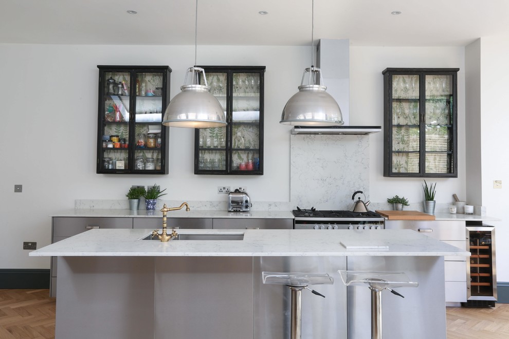 Idéer för att renovera ett mellanstort funkis linjärt kök och matrum, med en dubbel diskho, släta luckor, skåp i rostfritt stål, marmorbänkskiva, vitt stänkskydd, stänkskydd i marmor, rostfria vitvaror, ljust trägolv, en halv köksö och beiget golv