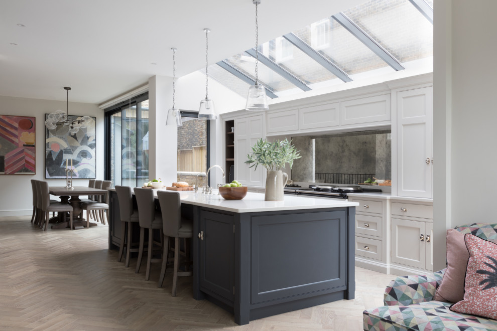 Foto di una cucina classica con ante a filo, ante grigie, paraspruzzi a effetto metallico, paraspruzzi a specchio, parquet chiaro, pavimento beige e top bianco