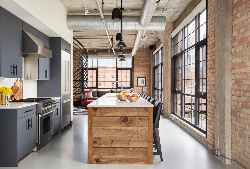 Inspiration for an industrial galley open plan kitchen in Minneapolis with grey cabinets, stainless steel appliances, white worktops, a submerged sink, flat-panel cabinets, white splashback, an island and grey floors.