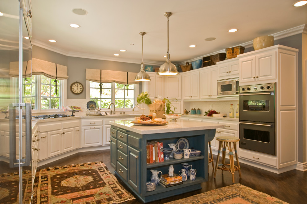Photo of a large traditional u-shaped enclosed kitchen in Los Angeles with a built-in sink, raised-panel cabinets, blue cabinets, soapstone worktops, white splashback, stainless steel appliances, dark hardwood flooring and an island.