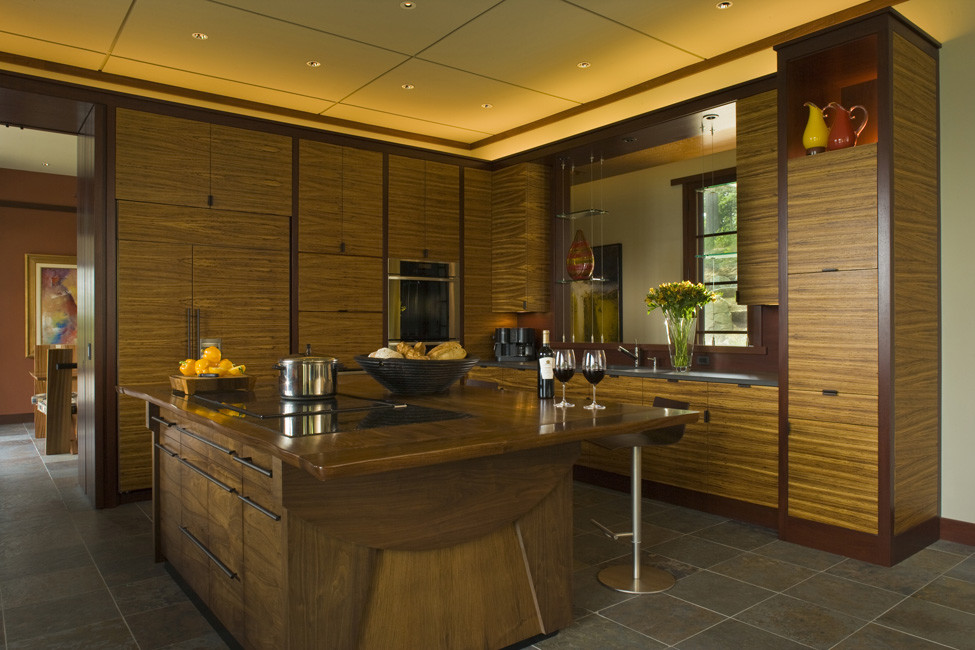 Aménagement d'une grande cuisine parallèle moderne en bois brun fermée avec un évier encastré, un placard à porte plane, un plan de travail en bois, un électroménager en acier inoxydable, îlot et un sol gris.