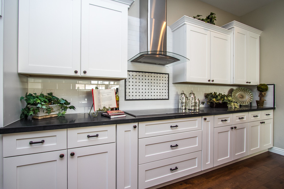 Foto på ett stort lantligt linjärt kök och matrum, med en rustik diskho, skåp i shakerstil, vita skåp, bänkskiva i kvartsit, vitt stänkskydd, stänkskydd i tunnelbanekakel, rostfria vitvaror, mellanmörkt trägolv och en köksö