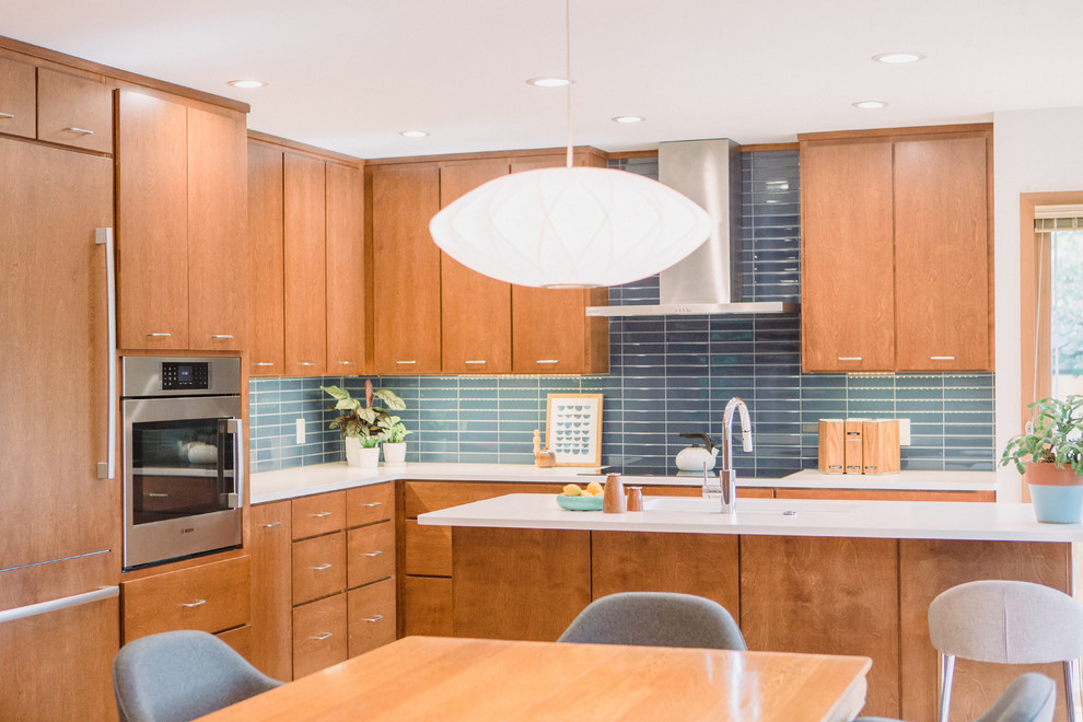 Exempel på ett mellanstort 50 tals vit vitt kök, med en undermonterad diskho, släta luckor, skåp i mellenmörkt trä, bänkskiva i kvarts, blått stänkskydd, stänkskydd i keramik, integrerade vitvaror, ljust trägolv, en köksö och brunt golv