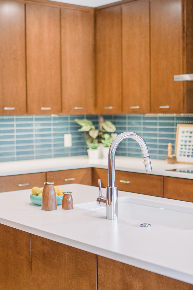 Medium sized retro l-shaped open plan kitchen in Grand Rapids with a submerged sink, flat-panel cabinets, medium wood cabinets, engineered stone countertops, blue splashback, ceramic splashback, integrated appliances, light hardwood flooring, an island, brown floors and white worktops.