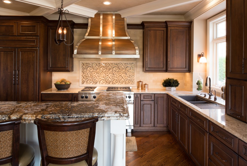 Design ideas for a large traditional l-shaped open plan kitchen in Minneapolis with a submerged sink, raised-panel cabinets, dark wood cabinets, beige splashback, ceramic splashback, stainless steel appliances, medium hardwood flooring and an island.