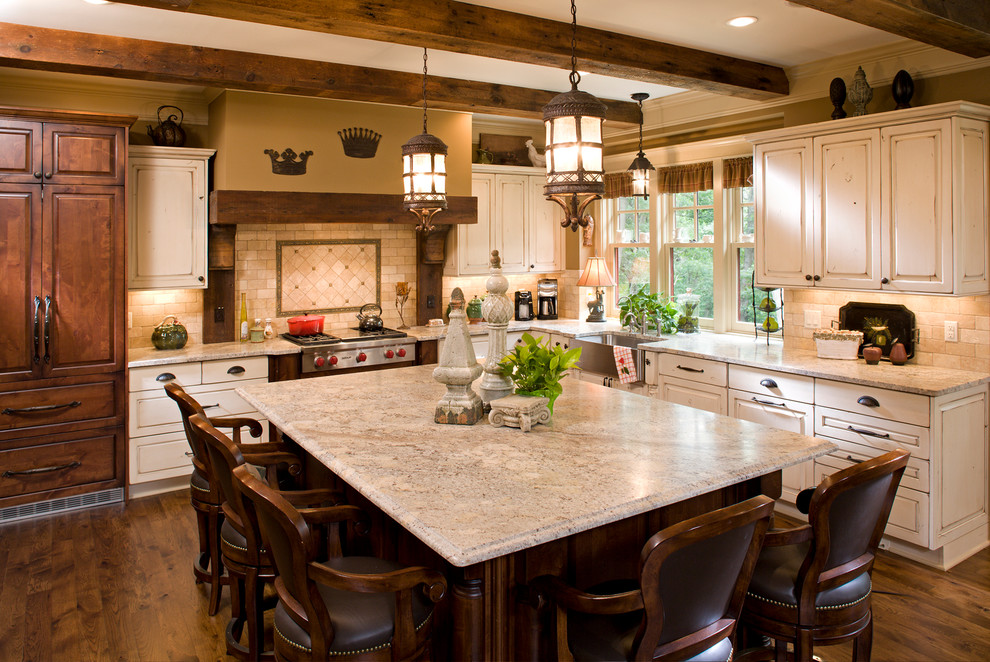Example of a large classic l-shaped medium tone wood floor open concept kitchen design in Minneapolis with a farmhouse sink, beige cabinets, raised-panel cabinets, an island, granite countertops, beige backsplash, paneled appliances and limestone backsplash