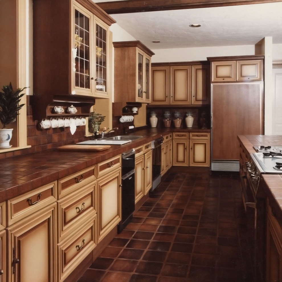 Exempel på ett stort klassiskt kök, med en dubbel diskho, luckor med infälld panel, beige skåp, kaklad bänkskiva, klinkergolv i terrakotta, en köksö och brunt golv