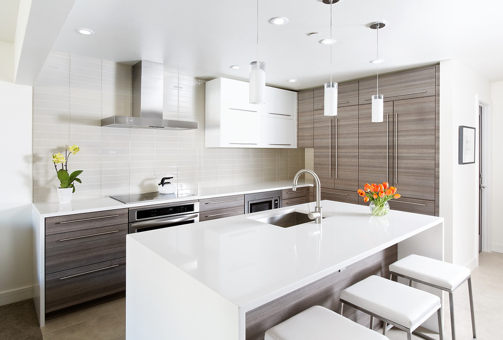 Design ideas for a medium sized modern l-shaped kitchen in Denver with a submerged sink, flat-panel cabinets, medium wood cabinets, composite countertops, white splashback, metro tiled splashback, stainless steel appliances, an island and porcelain flooring.