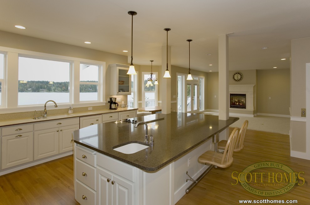 This is an example of a large arts and crafts l-shaped open plan kitchen in Seattle with beaded inset cabinets, white cabinets, granite benchtops, light hardwood floors and with island.