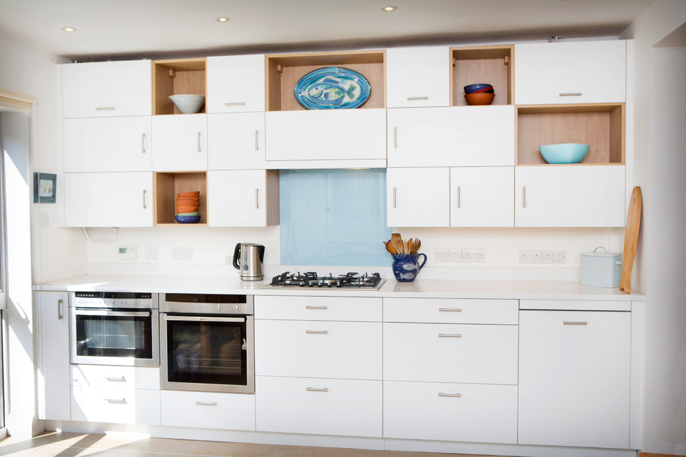 Exemple d'une petite cuisine américaine linéaire moderne avec un placard à porte plane, des portes de placard blanches et un plan de travail en granite.