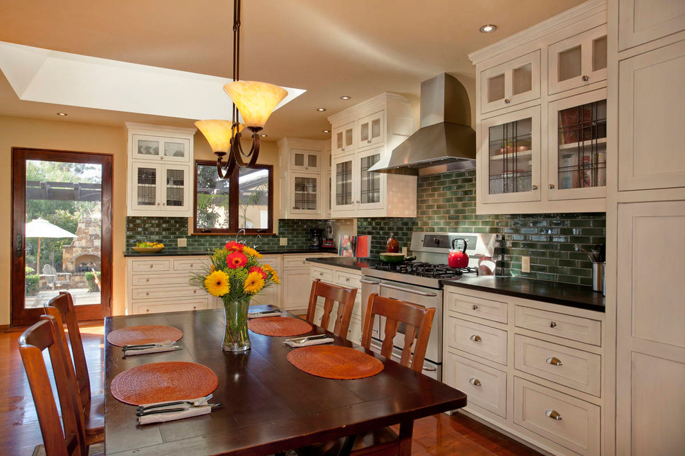 Klassische Wohnküche in L-Form mit Schrankfronten mit vertiefter Füllung, beigen Schränken, Küchenrückwand in Grün und Rückwand aus Metrofliesen in San Diego