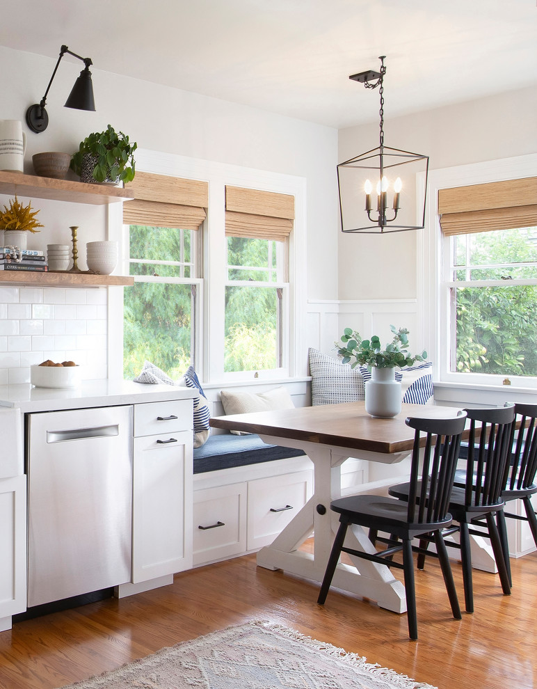 Cette image montre une cuisine américaine rustique avec un placard à porte shaker, des portes de placard blanches, un sol en bois brun, un sol marron et un plan de travail blanc.
