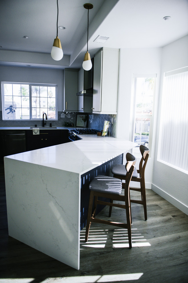 Example of a mid-sized minimalist u-shaped vinyl floor and gray floor eat-in kitchen design in San Diego with an undermount sink, flat-panel cabinets, blue cabinets, quartz countertops, gray backsplash, ceramic backsplash, black appliances, a peninsula and white countertops