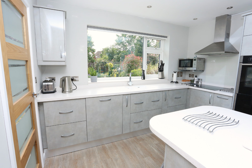 Photo of a medium sized modern l-shaped enclosed kitchen in Other with an integrated sink, flat-panel cabinets, grey cabinets, composite countertops, an island and white worktops.