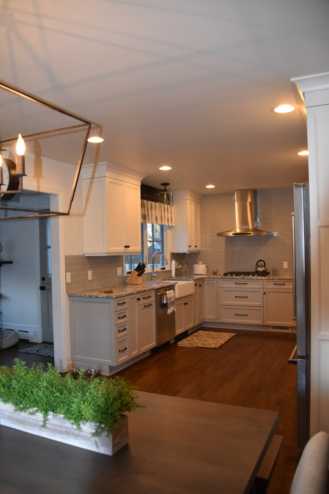 Example of a mid-sized country u-shaped dark wood floor and brown floor eat-in kitchen design in New York with a farmhouse sink, white cabinets, granite countertops, gray backsplash, glass tile backsplash, stainless steel appliances, no island, multicolored countertops and recessed-panel cabinets