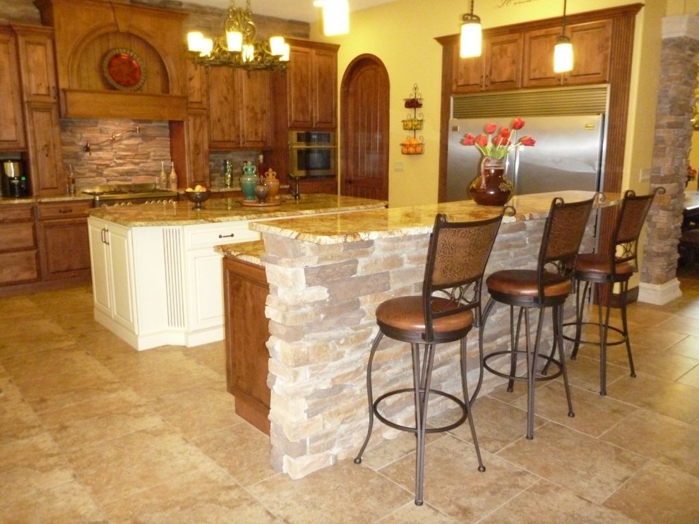 Rustik inredning av ett mellanstort kök, med en rustik diskho, luckor med upphöjd panel, skåp i slitet trä, granitbänkskiva, flerfärgad stänkskydd, stänkskydd i sten, rostfria vitvaror, klinkergolv i porslin, flera köksöar och beiget golv