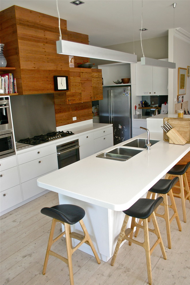 Идея дизайна: кухня-гостиная в современном стиле с плоскими фасадами, белыми фасадами, фартуком цвета металлик, фартуком из металлической плитки и техникой из нержавеющей стали