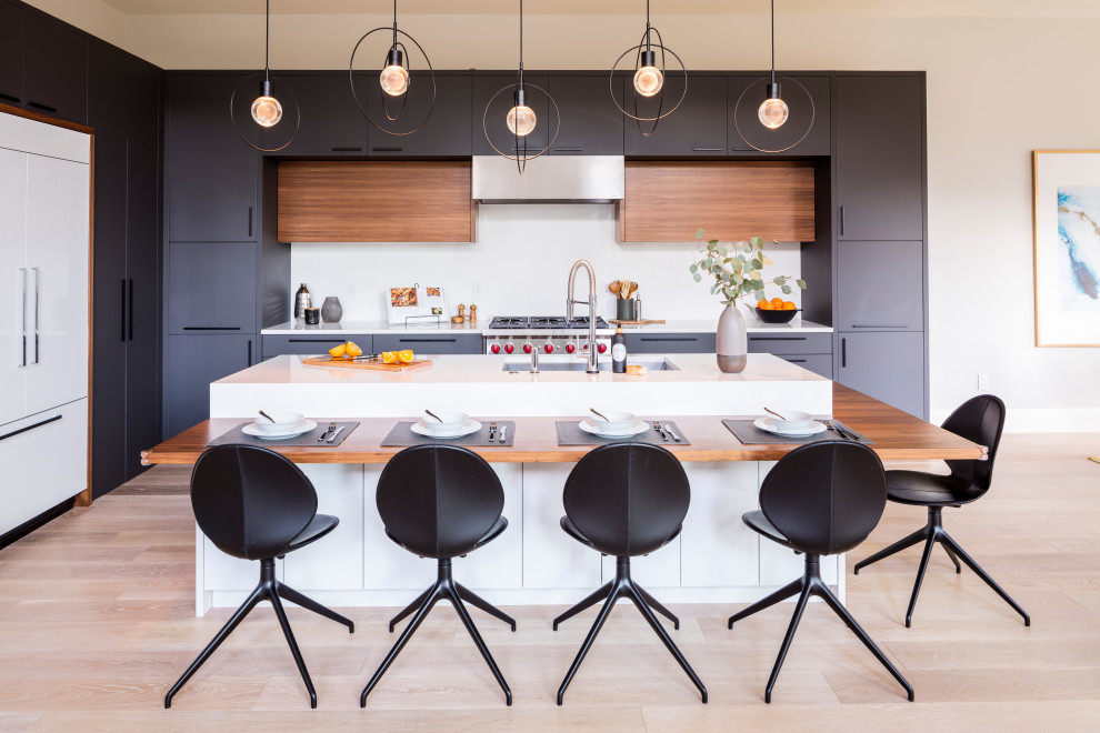 Photo of a modern l-shaped kitchen in Seattle with flat-panel cabinets, grey cabinets, granite worktops, white splashback, stone slab splashback, integrated appliances, light hardwood flooring and white worktops.