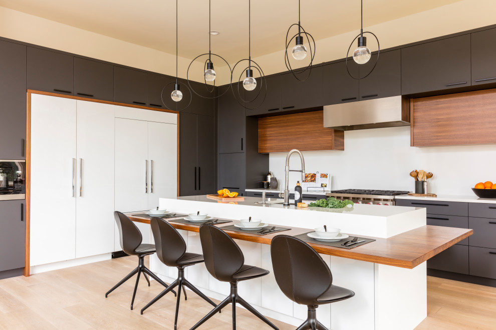 Moderne Küche in L-Form mit flächenbündigen Schrankfronten, Granit-Arbeitsplatte, Küchenrückwand in Weiß, Rückwand aus Stein, Elektrogeräten mit Frontblende, hellem Holzboden, weißer Arbeitsplatte, Kücheninsel und beigem Boden in Seattle
