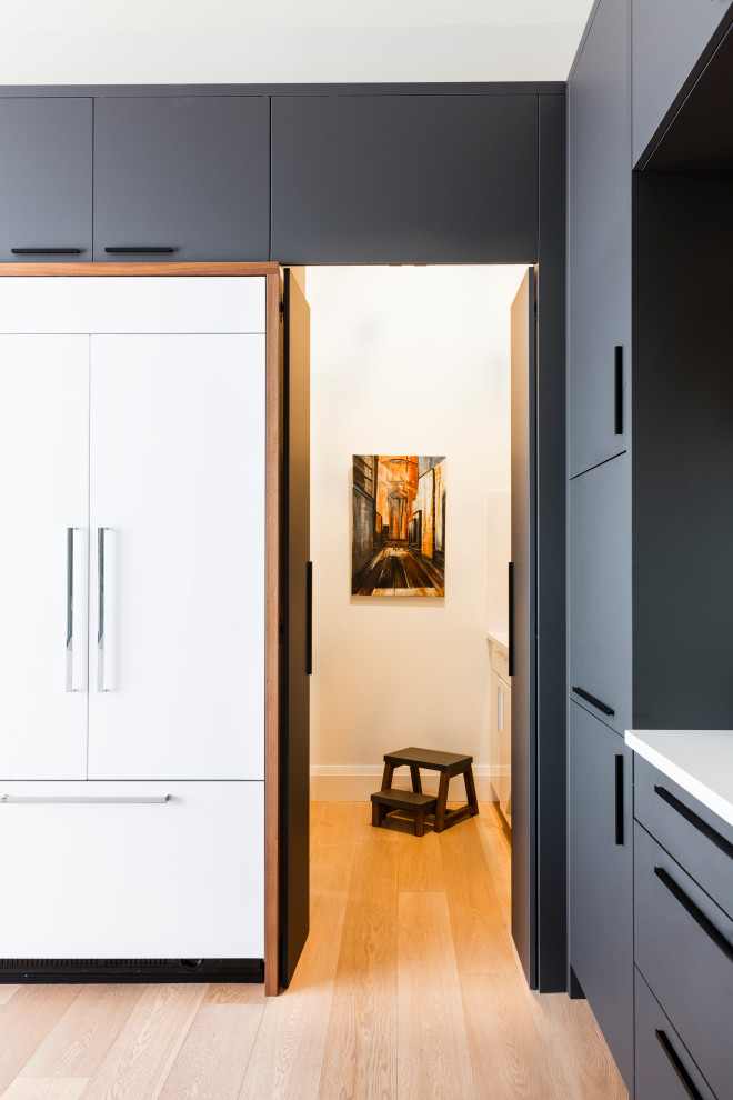 Minimalist l-shaped light wood floor kitchen photo in Seattle with flat-panel cabinets, gray cabinets, granite countertops, white backsplash, stone slab backsplash, paneled appliances and white countertops