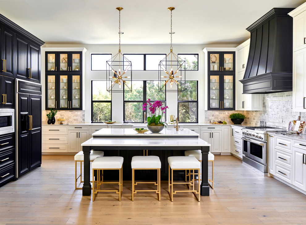Example of a transitional u-shaped light wood floor and beige floor kitchen design in Austin with a farmhouse sink, raised-panel cabinets, black cabinets, gray backsplash, paneled appliances, an island, white countertops and quartz countertops