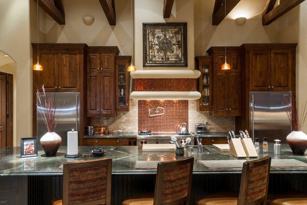 Modelo de cocina tradicional con armarios con paneles con relieve, puertas de armario de madera en tonos medios y electrodomésticos de acero inoxidable
