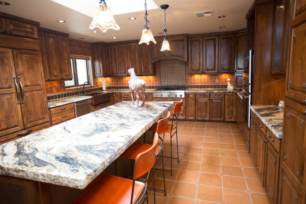 Example of a large southwest u-shaped terra-cotta tile and orange floor eat-in kitchen design in Phoenix with a farmhouse sink, raised-panel cabinets, distressed cabinets, granite countertops, multicolored backsplash, terra-cotta backsplash, paneled appliances and an island
