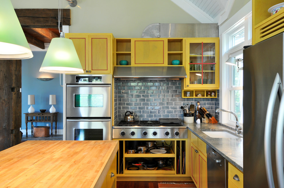 Inredning av ett modernt mellanstort kök, med luckor med infälld panel, gula skåp, en undermonterad diskho, granitbänkskiva, blått stänkskydd, stänkskydd i tunnelbanekakel, rostfria vitvaror, mörkt trägolv och en köksö