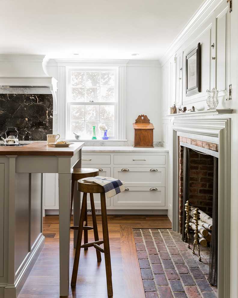 Klassische Küche mit Landhausspüle, Schrankfronten im Shaker-Stil, Küchengeräten aus Edelstahl, braunem Holzboden, Kücheninsel, Quarzit-Arbeitsplatte, Küchenrückwand in Schwarz und Rückwand aus Stein in Boston