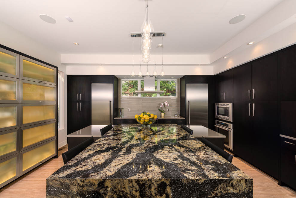 Trendy l-shaped light wood floor eat-in kitchen photo in Indianapolis with flat-panel cabinets, black cabinets, gray backsplash, stainless steel appliances and two islands
