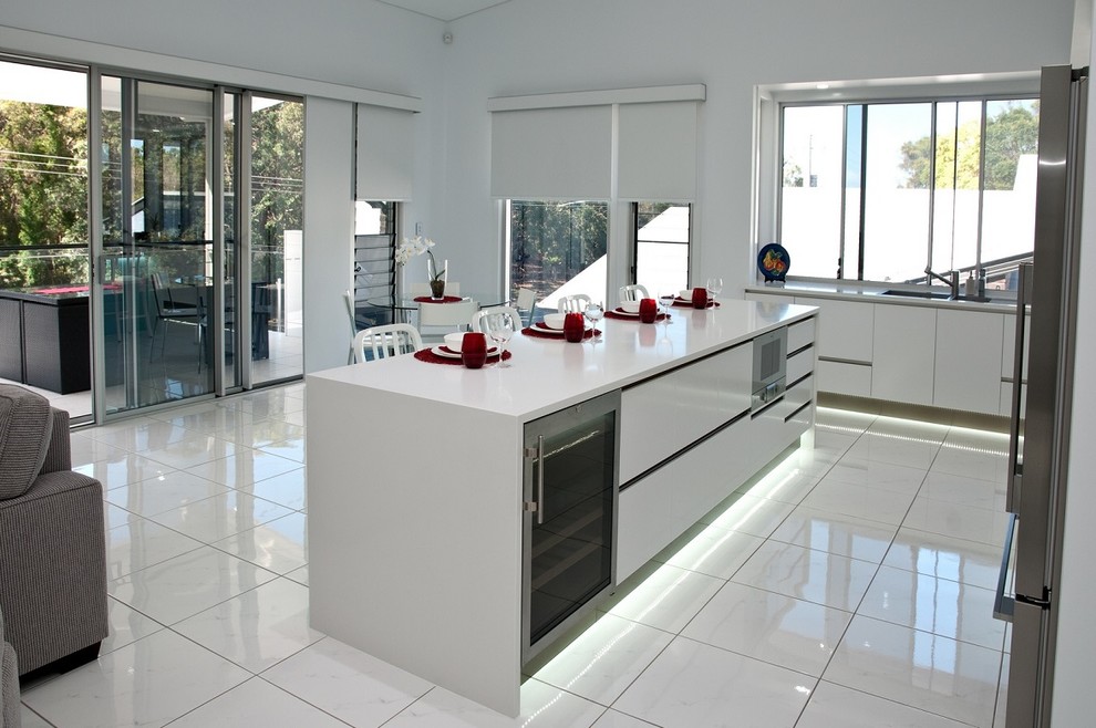 This is an example of a contemporary u-shaped open plan kitchen in Brisbane with flat-panel cabinets, white cabinets and an island.