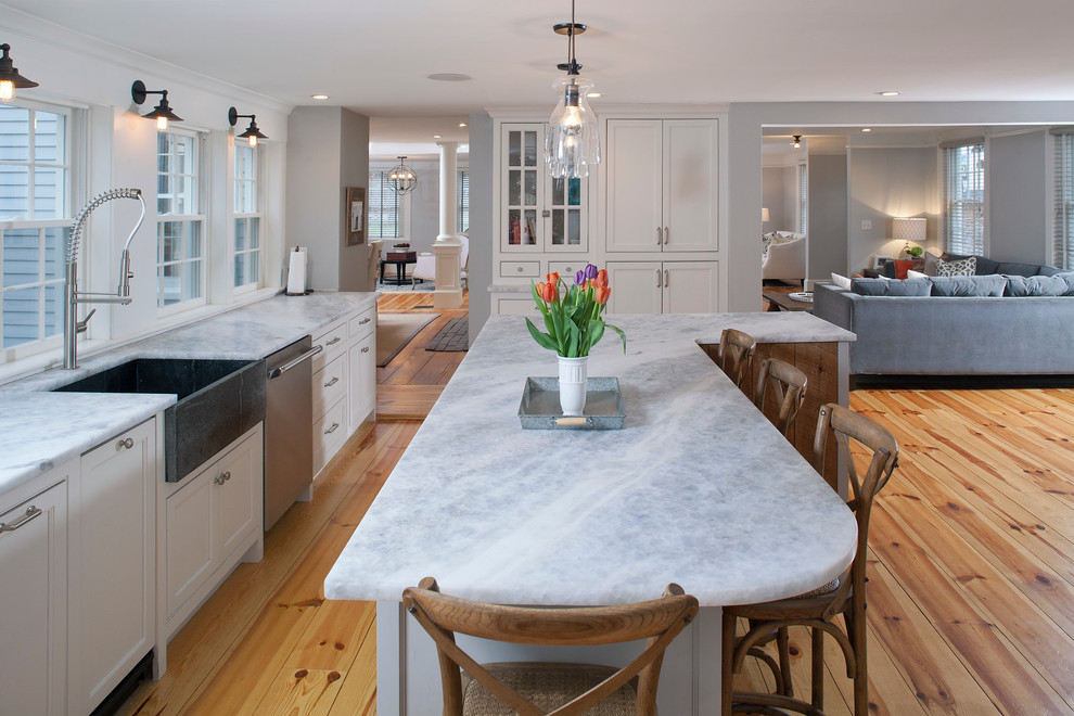 Inspiration for a large transitional u-shaped light wood floor open concept kitchen remodel in Boston with a farmhouse sink, beaded inset cabinets, white cabinets, quartzite countertops, white backsplash, ceramic backsplash, stainless steel appliances and an island