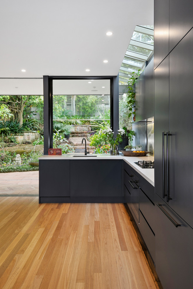 シドニーにあるコンテンポラリースタイルのおしゃれなキッチン (アンダーカウンターシンク、黒いキャビネット、クオーツストーンカウンター、緑のキッチンパネル、大理石のキッチンパネル、黒い調理設備、無垢フローリング、アイランドなし、白いキッチンカウンター) の写真