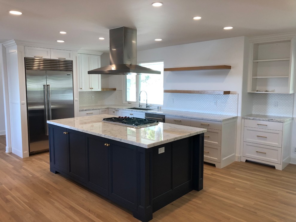 This is an example of a medium sized classic l-shaped kitchen/diner in Orange County with a submerged sink, recessed-panel cabinets, white cabinets, granite worktops, white splashback, ceramic splashback, stainless steel appliances, light hardwood flooring, an island, brown floors and white worktops.